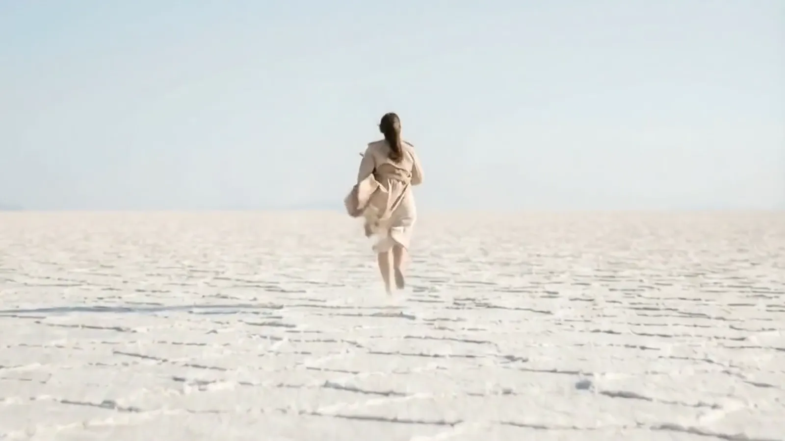 A runner crossing white salt flats under an open sky